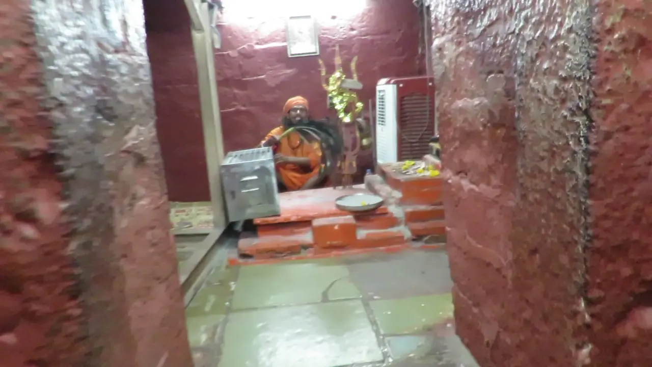 भर्तृहरि गुफा, उज्जैन के भीतर: लाल रंग से पुते पाषाण-कक्ष में बैठे एक नाथ साधु (2018)